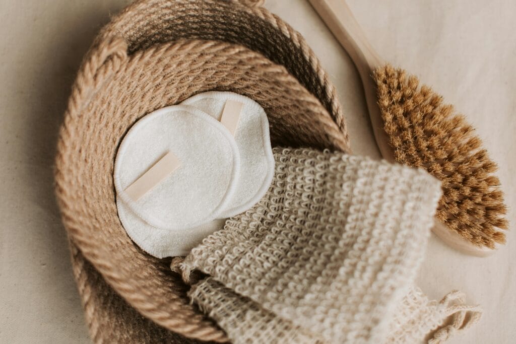 A top view of eco-friendly skincare items like cotton pads and brush in a jute basket used in a blog in the section How to use micellar water